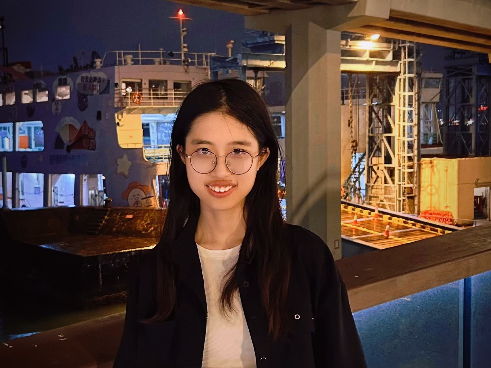 Zirui Zhou smiling beside a warmly lit harbor